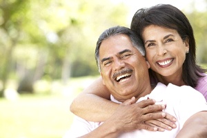 Older couple with all on 4 dental implants hugging and smiling