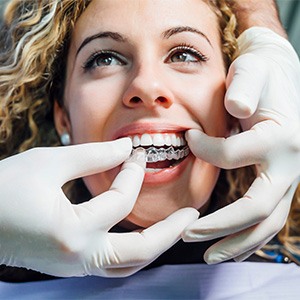 a dentist showing a patient how to put in their invisalign trays