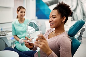 a patient looking in a handheld mirror at a dental office