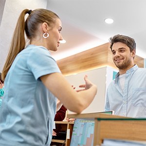 a woman at a dental office front desk talking to a patient