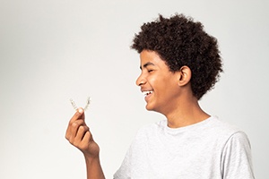 smiling teen looking at Invisalign Teen aligner