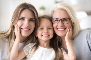 mom, daughter, and grandmother hugging and smiling