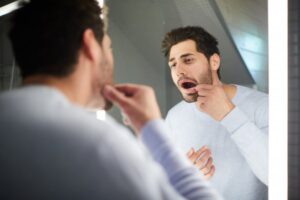 man looking in the mirror at his teeth