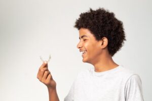 young man holding and smiling at Invisalign aligners